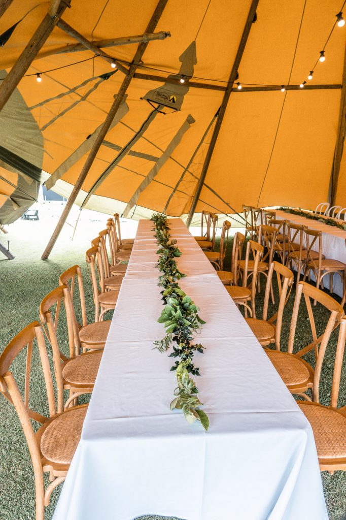 feasting tables in tipis with greenery runners